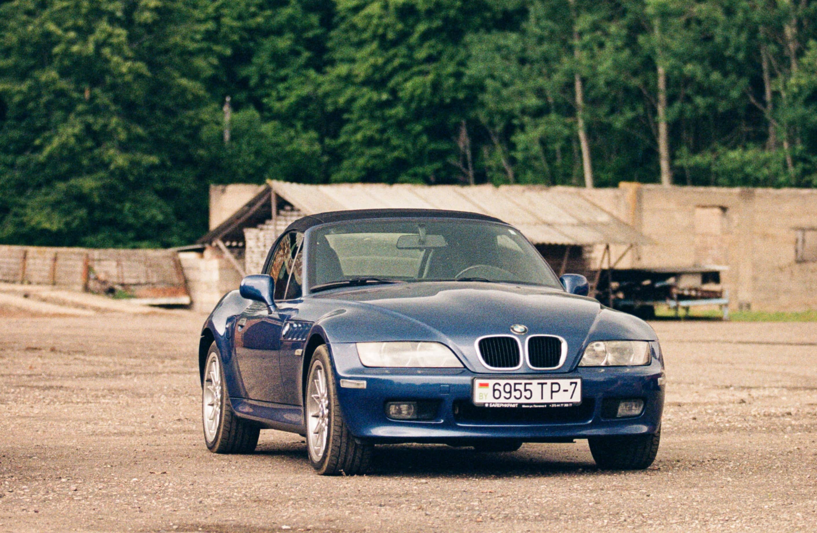 Blue BMW Z3 roadster parked outside. Front view of the car with its headlights, grill, and license plate visible.